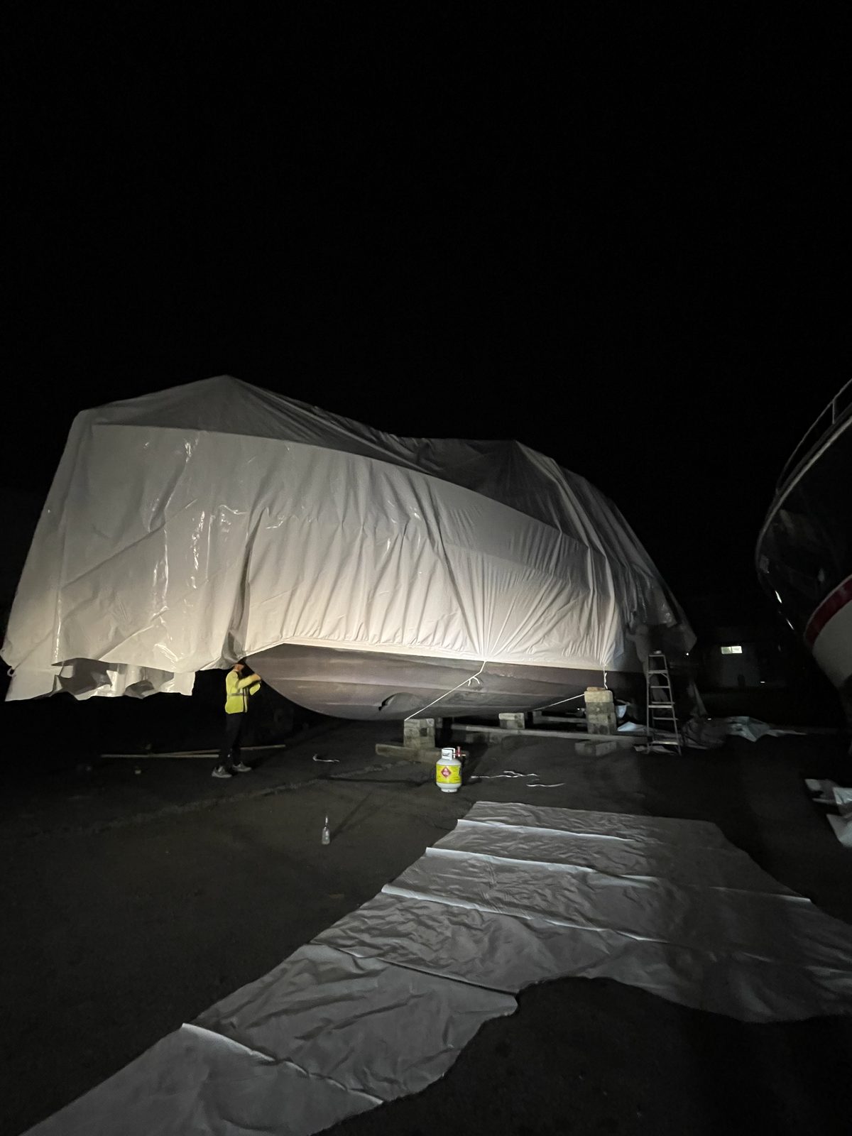 Shrink wrapped cruiser finished at night in the marina yard