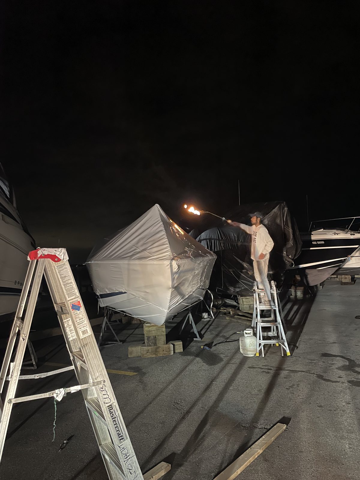 Heat gun sealing shrink wrap film on a boat after dark